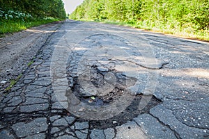 Dangerous pothole in the asphalt rural road. Road damage photo