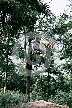 Dangerous ride. Young active man riding bmw bike outdoors in forest, park, training and doing difficult tricks in the