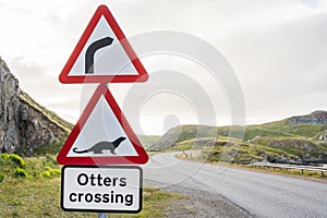 Dangerous right curve and Otters crossing ahead. Red warning road sign along a highway in the scottish highlands. Scotland, UK