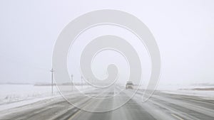 Dangerous road with ice and blizzard, view from car on icy highway. Treacherous journey through icy conditions