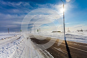 Dangerous snowing empty road with crosswalk, bus stop and road signs for driving cars and public transport during blizzard