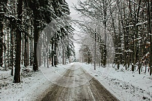 Dangerous stretch of road covered with snow and ice.Snowy road through forest.Winter panorama.Driving in icy frozen