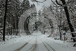 Dangerous stretch of road covered with snow and ice.Snowy road through forest.Winter panorama.Driving in icy frozen landscape.Bad
