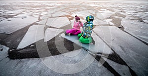 Dangerous thin ice. Children broke into the ice in winter. Children boy and girl sitting on broken ice in water. Deep