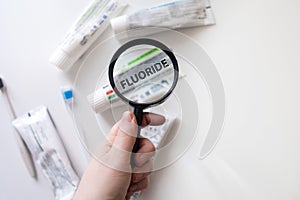 Dangerous toothpaste ingredient fluoride. Checking the composition of toothpaste with a magnifying glass against the background of photo