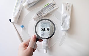 Dangerous toothpaste ingredient SLS, sodium laureth sulfate. Checking the composition of toothpaste with a magnifying glass