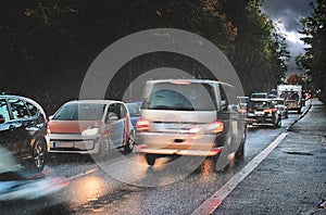 Dangerous traffic in autumn, rush hour with braking cars in the rain on wet asphalt in a narrow street on the way to business work