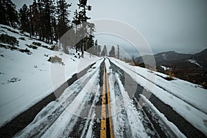 Dangerous uncleared slippery asphalt winter road with snow in mountains.