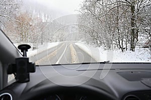 Dangerous winter season with snow on the road. The interior of the car from the driver`s point of view - dangerous traffic in bad
