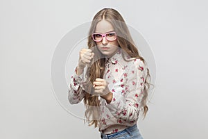 Dangerous young woman in pink eyeglasses, looking at camera and