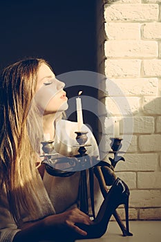 Dangerously cute. Woman with high heel shoe and candlestick with snake. Young woman with long hair hold fashion shoe photo