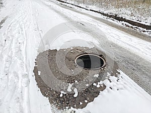 Dangerously open hatch on the road without warning fences. Danger on the road. Snowy road with an open hatch