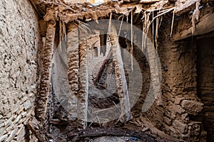 Dangling roof beams of abandoned house in ruins of Birkat al Mawz, Oman