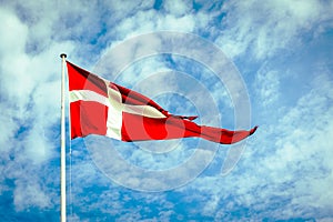 Danish Flag, the Dannebrog, in front of a blue and cloudy sky. photo