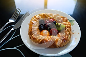 Danish pastry with remix fruits on the white plate in the morning background. Dark tone