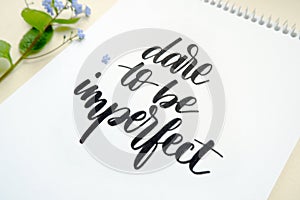 Dare to be imperfect, motivational quote on white paper