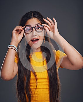 Dare to be yourself. Cropped portrait of an attractive teenage girl wearing glasses and feeling playful against a dark