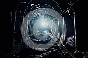 Dark abandoned coal mine with rusty lining in backlight