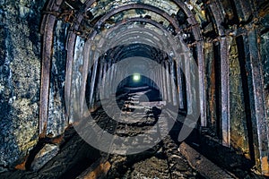 Dark abandoned coal mine with rusty miner stands