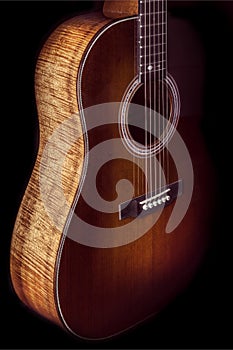Dark amber sunburst acoustic guitar with koa wood sides in dramatic lighting