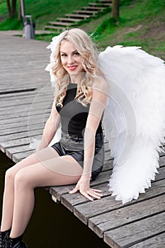 dark angel. blonde sexy woman in black leather clothes with white angels wings