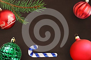 Dark background with Christmas fir branch, stick, red wavy dull and green ribbed ball