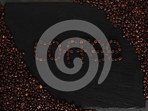 Dark background with coffeeped phrase Coffe. Black texturised background with coffee beans.