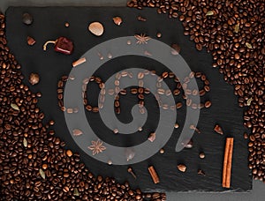 Dark background with coffeeped phrase Coffe. Black texturised background with coffee beans and spices.