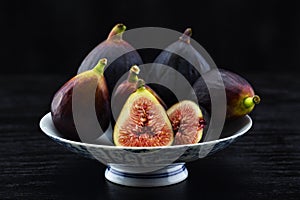 Dark background still life of fig fruit on footed dish