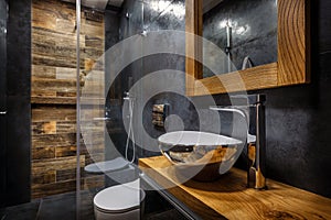 Dark bathroom interior with shower. Tiles imitating wood on the floor and on the wall