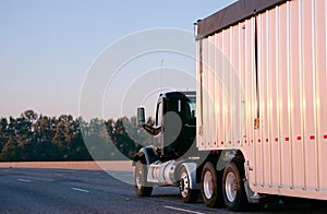 Dark big rig semi truck with day cab carry huge bulk trailer run