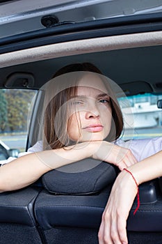 Dark blond young woman in car trunk