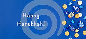 Dark blue background with dreidels and chocolate coins and Happy Hanukkah wording. Hanukkah and judaic holiday concept.