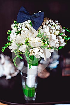 Dark blue bow tie on a luxury bridal bouquet of white flowers on a shelf