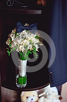 Dark blue bow tie on a luxury bridal bouquet of white flowers on a shelf