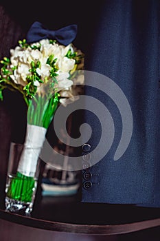 Dark blue bow tie on a luxury bridal bouquet of white flowers on a shelf