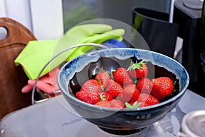 Dark blue bowl of strawberries in a kitchen