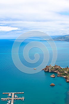 Dark blue calm water of Tyrrhenian sea surrounding the Sicilian coastal village Cefalu from above. Captured on vertical picture