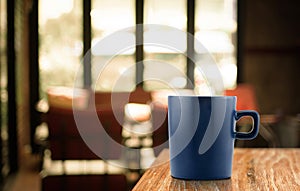 Dark Blue Coffee cup on wood table in blur cafe background