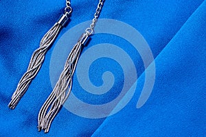 Dark blue colored fabric background with two silver pendants.