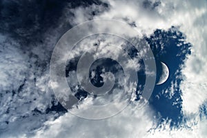 Dark blue dramatic sky background with white clouds and moon. Beautiful atmospheric cloud scape. Cumulus clouds