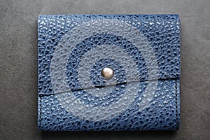 Dark blue leather wallet on a dark background top view. Close-up, purse details, rivet and firmware