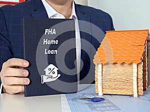 Dark blue notepad in a hand with phrase FHA Home Loan . Horizontal shot. Close-up