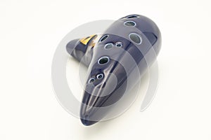 A dark blue ocarina in front of white background photo