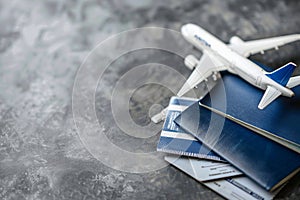 Dark blue passports, tickets and toy model of airplane on a grey background