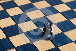 Dark blue pawn on wooden chessboard