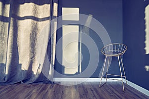 Dark blue room with modern chair on high legs, metal frame with soft seat, curtains, window shadow, brown wooden floor