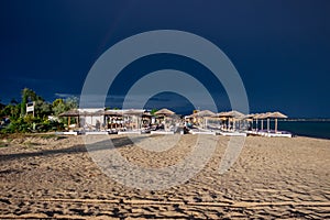 The dark blue sky is above the beach bar by the sea. It`s like a storm. The beach is empty and there are no people