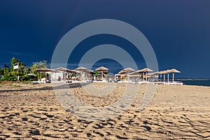 The dark blue sky is above the beach bar by the sea. It`s like a storm. The beach is empty and there are no people