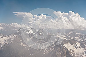 Dark blue sky with clouds on the rocky peaks of the mountains covered with glaciers and snow